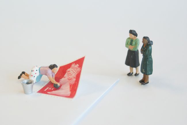 Small model figures adding a stamp to a letter