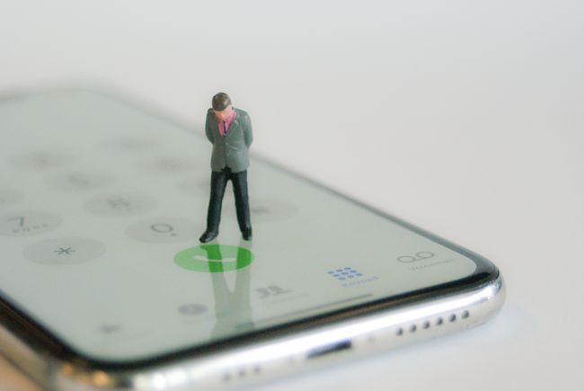 Small model figure standing on mobile phone