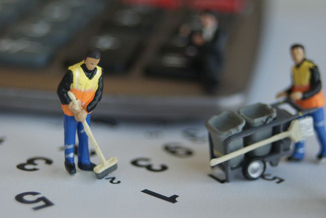 Small model figures dressed as bin men sweeping up numbers