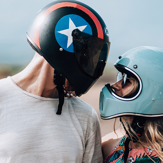 couple looking at each other in motorcycle helmets